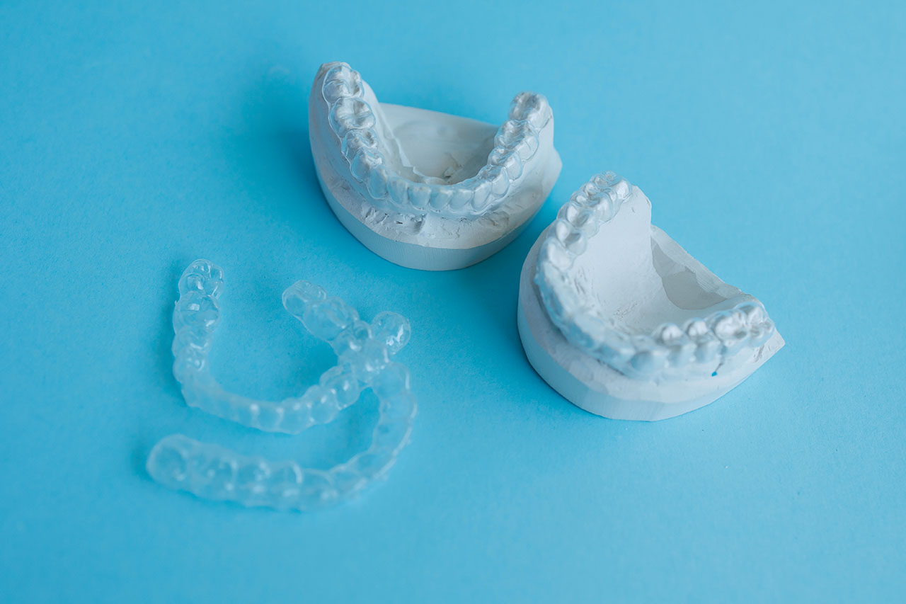 Clear retainers are shown on models of teeth, demonstrating how they help maintain a straight smile after braces.