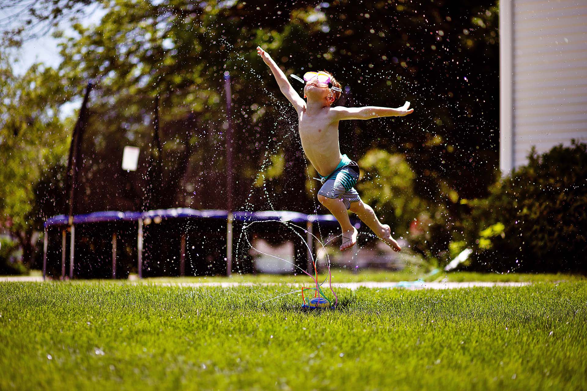 Child plays in the sprinklers during summer to beat the heat