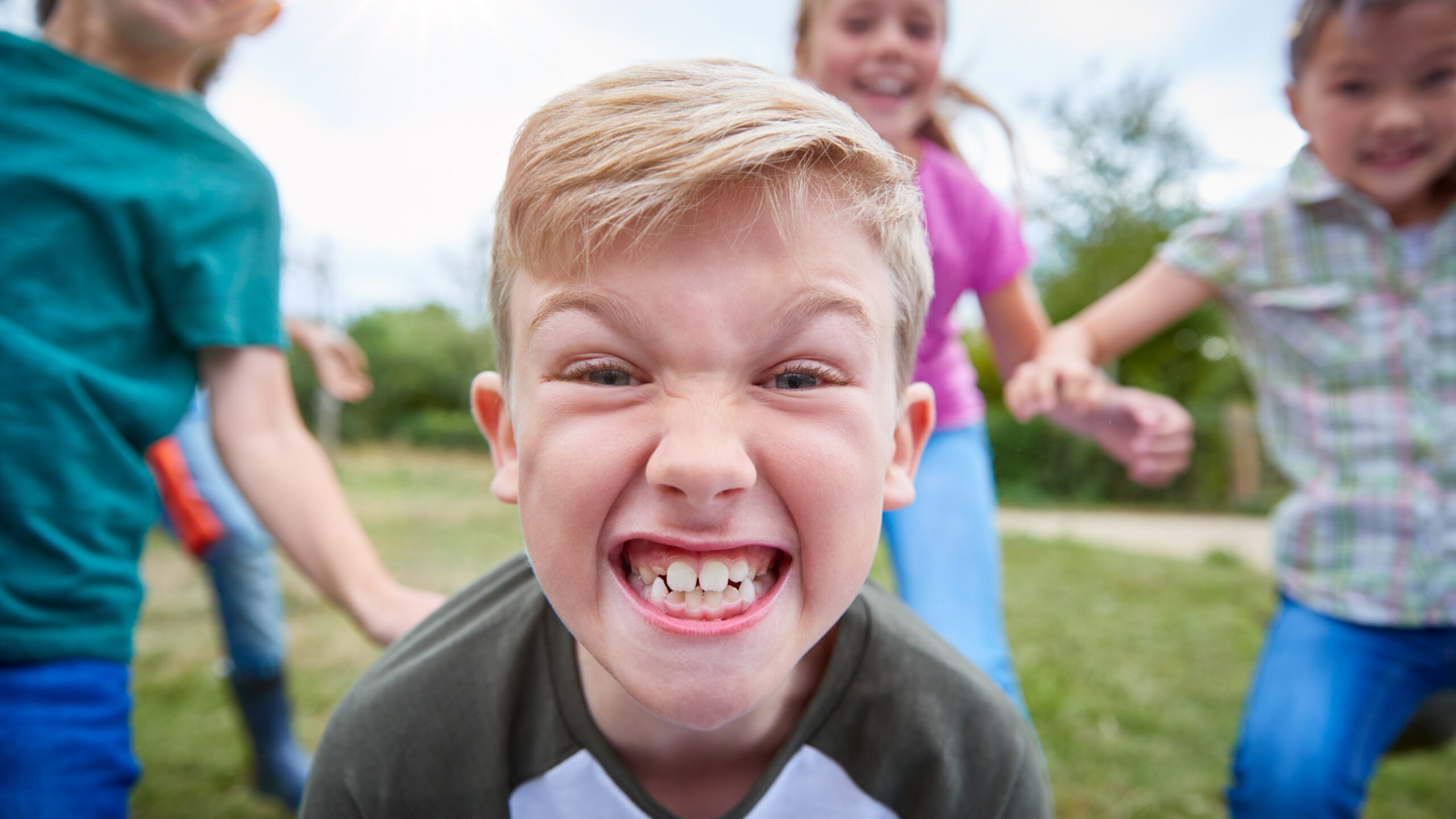 Happy children playing outdoors, showing healthy smiles despite potential crossbites or overbites.