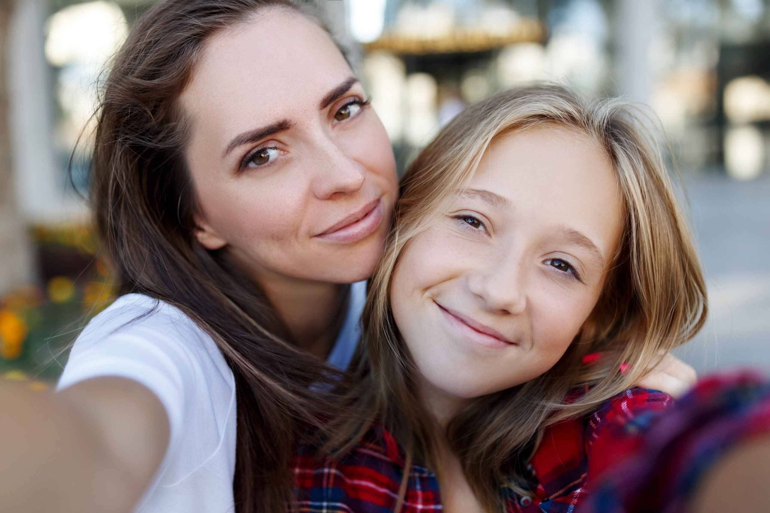 Happy mother and teenage daughter taking a selfie, showing their smiles after getting braces.