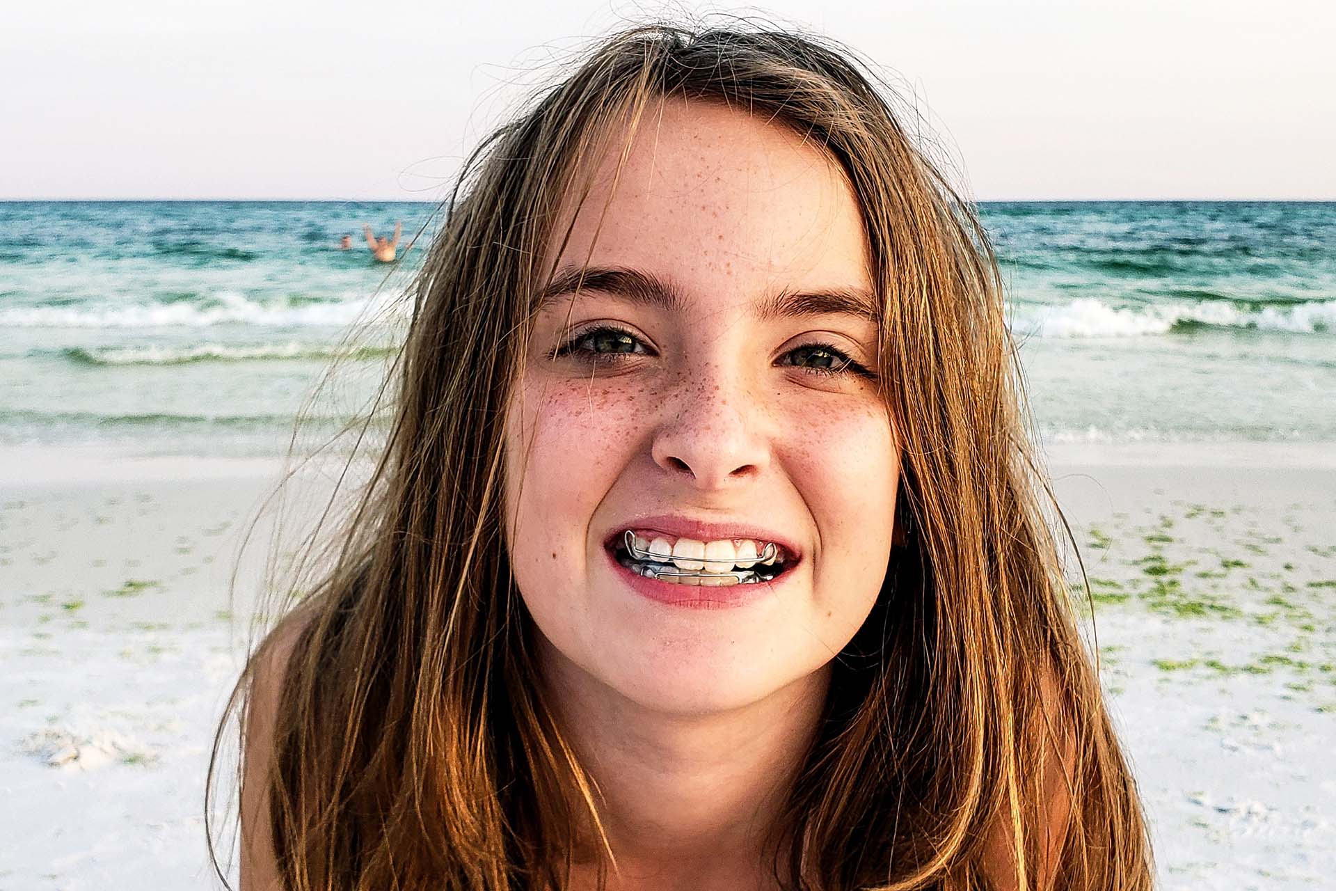 smiling girl wearing her retainer at the beach